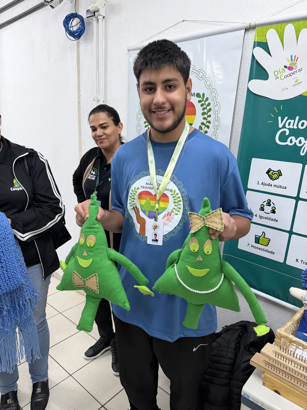 Aluno segurando os mascotes verdes do cooperativismo em uma escola visitada