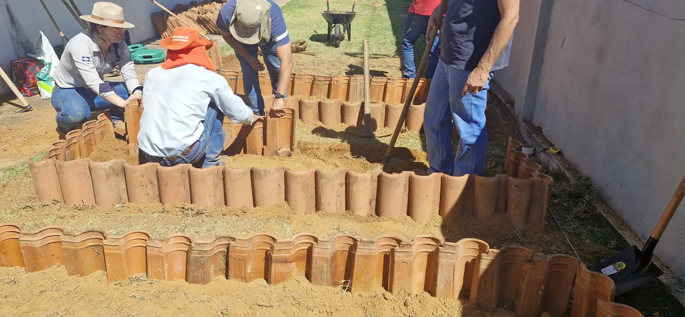 Alunos montando os canteiros com telhas de barro