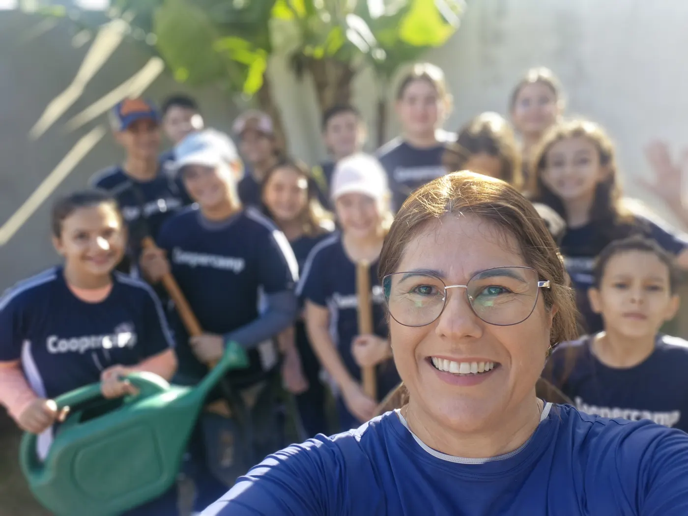 Alunos e professora reunidos na horta, com regadores